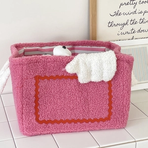 Detail of pink fleece monster storage basket with red wavy trim and striped interior lining
