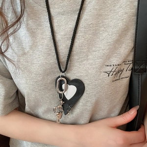 Detail of minimalist leather heart and silver puppy pendant on a black woven cord necklace