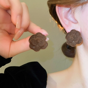 Detailed close-up of vintage chocolate flocked camellia earrings on model's ear