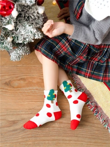 Detailed close-up of a white cotton Christmas sock with green tree pattern and red heels