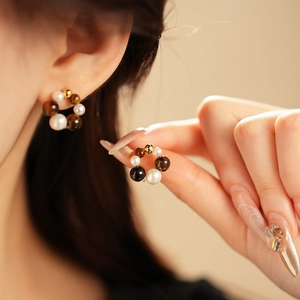 Detail of vintage round pearl earrings with amber beads worn by a model in soft light