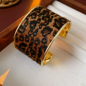 Detail of gold-edged cuff bracelet with leopard print texture on velvet background