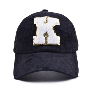 Close-up of distressed baseball cap with white K patch and gold sequin edge detail