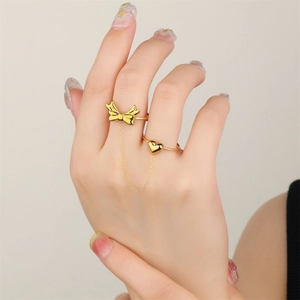 Detail of 18k gold butterfly and heart double finger ring connected by a dainty chain