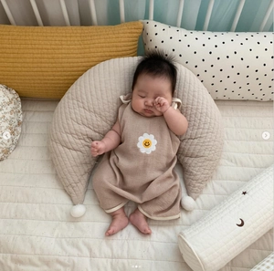 Close-up of khaki waffle knit cotton texture on a moon-shaped baby nursing pillow