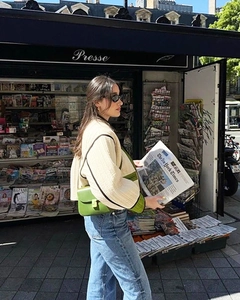 Detail of a bright green flap shoulder bag paired with a beige quilted jacket in the street