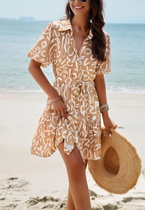 Short sleeve shirt dress featuring geometric print and ruffled hem on a sunny beach