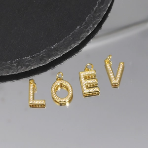 Detailed view of gold-plated letter pendants L O V E inlaid with cubic zirconia crystals