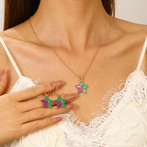 Star and moon jewelry set with green and purple enamel pendants on a gold necklace
