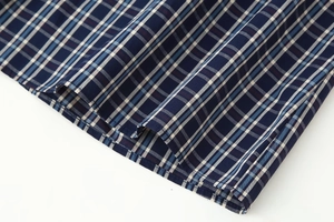 Detailaufnahme der dunkelblauen Karostoffstruktur und Saumnaht am Midi-Kleid