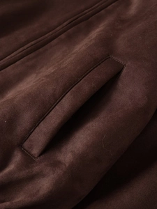 Detail der dunkelbraunen Wildlederimitat-Jacke mit Reißverschlusstasche und Stoffstruktur