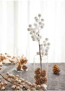 Elegant white and gold Christmas berry branches in a glass vase with pinecones
