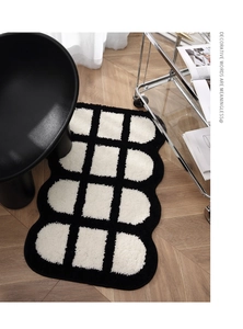 Dettaglio del soffice tappeto bianco e nero con motivi geometrici su pavimento in legno