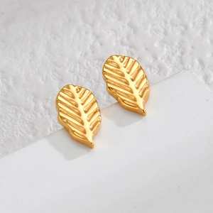 Golden stainless steel leaf stud earrings with detailed vein texture on white pedestal