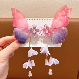 Detail of butterfly hair clips with pink gradient wings and floral tassel charms