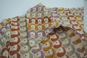 Detailed close-up of bohemian crochet knit fabric with colorful wave patterns and textures