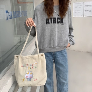 Détail d'un sac cabas en velours côtelé beige avec broderies de lapin et d'œuf