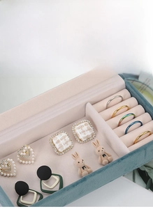 Detailed view of dark green velvet jewelry box with pink lining and organized rings