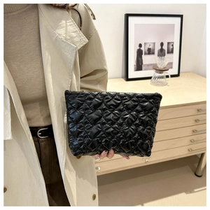 Detail of heart-quilted black makeup bag held by a model for professional storage
