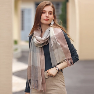 Elegant plaid fringe scarf in neutral tones worn by a model in a cozy autumn street setting