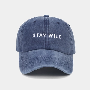 Close-up of white STAY WILD embroidery on vintage washed blue cotton baseball cap