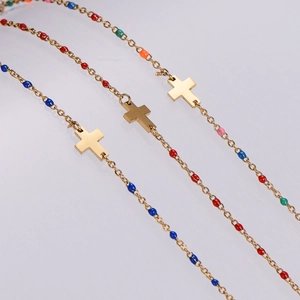 Dettagli di catene dorate con perle di smalto colorate e un pendente a croce semplice