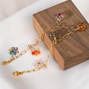 Dettaglio del bracciale dorato con ciondoli a fiori di cristallo su base di legno