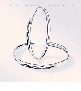 Detailed view of silver hoop earrings featuring a diamond-cut textured surface design