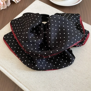 Close-up of a polka dot fabric bow banana hair clip on a vintage background