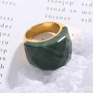Macro shot of 18K gold ring with multi-faceted dark green gemstone and thick band