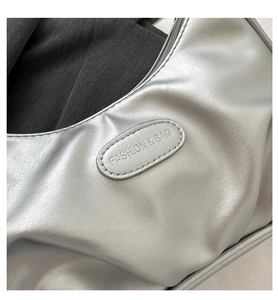 Dettaglio di una borsa a mezzaluna argento con texture metallica e logo del marchio
