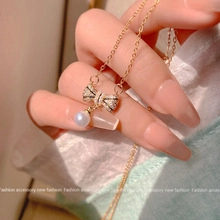 Detail of gold butterfly pendant with sparkling stones and a round white pearl charm