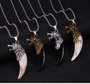 Close-up of punk style wolf tooth necklaces with carved metal heads and resin pendants