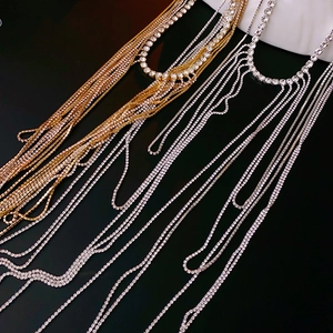 Gros plan d'un collier à pompons en strass avec des chaînes argentées et dorées