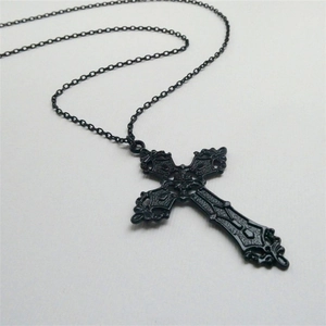 Gothic large black metal cross necklace with embossed patterns on minimalist light background