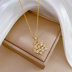 Macro shot of gold swan pendant with clear crystals on luxury beige jewelry box