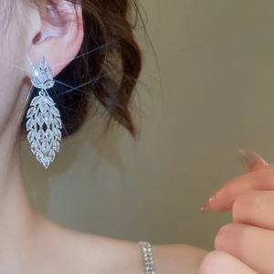 Close-up of model wearing silver tassel earrings with marquise-cut zircon floral details
