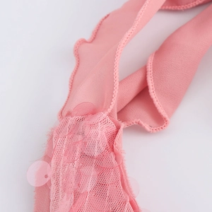 Détail macro des paillettes roses et du tissu en maille sur la robe dos nu licou