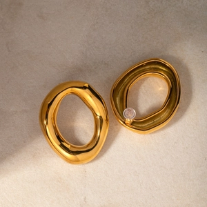 Macro view of 18k gold plated stainless steel hollow oval earrings on marble