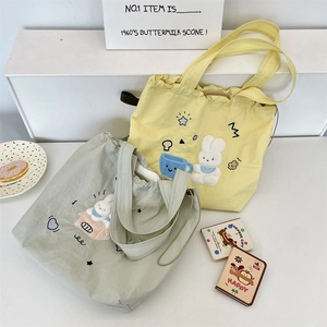 Dettaglio della borsa tote in tela ricamata con chiusura a coulisse in colori pastello