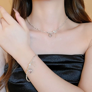 Close-up of model wearing silver bow necklace and bracelet set with pink heart gemstone
