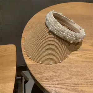 Detailed close-up of straw sun visor with faux pearl embellishments on the brim