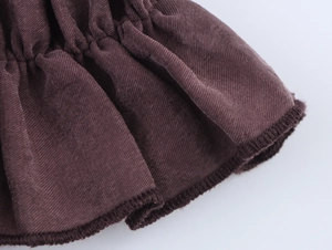Detailed view of dark brown knitted fabric with ruffle edge and textured weave pattern