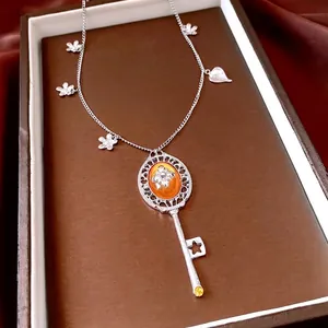 Vintage silver key necklace with orange resin gemstone and floral design accents
