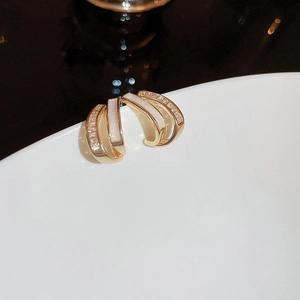 Detailed macro view of gold C-shaped earring with zircon stones and mother-of-pearl inlay