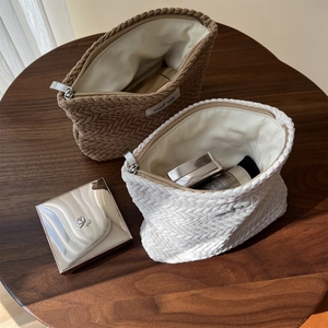 Close-up of textured knit makeup bags in beige and brown with woven 'simple wish' label