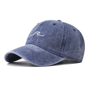 Close-up of white wave embroidery on a navy blue washed denim baseball cap
