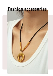 Detailopname van een 18k vergulde hoorn hanger aan een zwart koord gedragen door een model