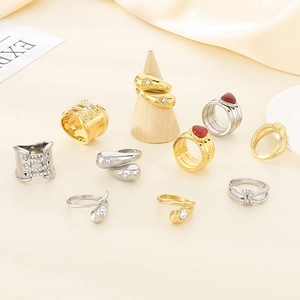 Detail of 18K gold plated knotted rings and teardrop rhinestone bands on beige fabric