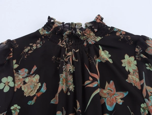 Details des gesmokten Stehkragens und Blumenmusters auf dem Chiffon-Langarmkleid